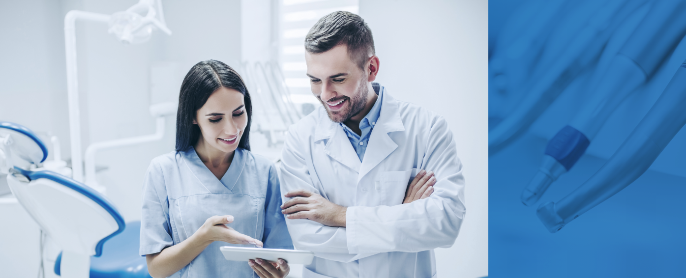 Ein Arzt und eine Ärztin stehen in einer Praxis und blicken auf ein Tablet.